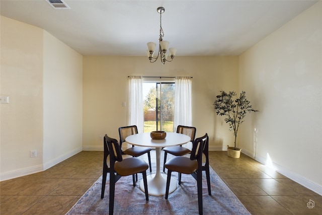 dining area with a chandelier and dark tile patterned flooring