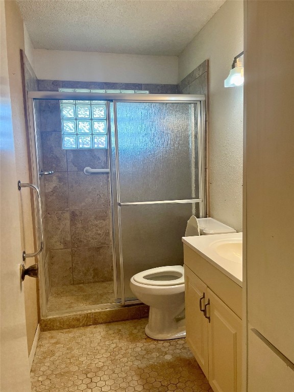 bathroom featuring vanity, tile patterned flooring, a shower with shower door, a textured ceiling, and toilet