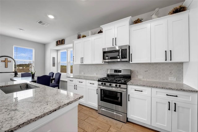 121 Woods Edge Ln, Georgetown, TX 78628 - kitchen with appliances with stainless steel finishes, backsplash, white cabinets, light stone countertops, and recessed lighting
