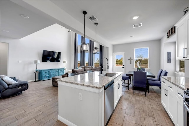 121 Woods Edge Ln, Georgetown, TX 78628 - kitchen featuring open floor plan, appliances with stainless steel finishes, light wood-style floors, and light stone counters
