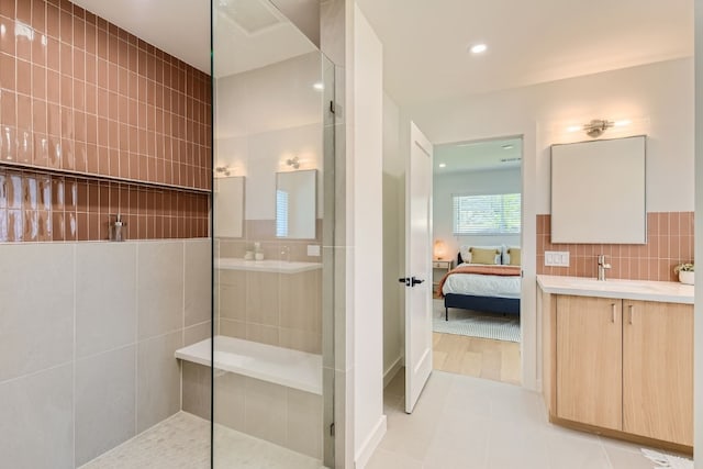 bathroom with tile walls, vanity, a shower, and wood-type flooring