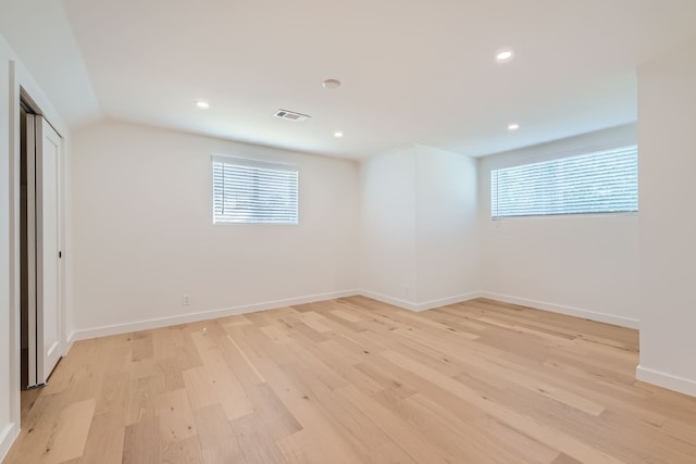 unfurnished bedroom with light wood-type flooring, a closet, and multiple windows