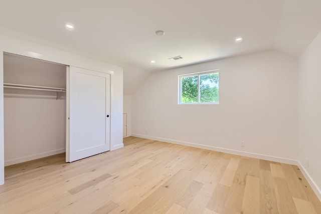 additional living space with light hardwood / wood-style flooring and lofted ceiling