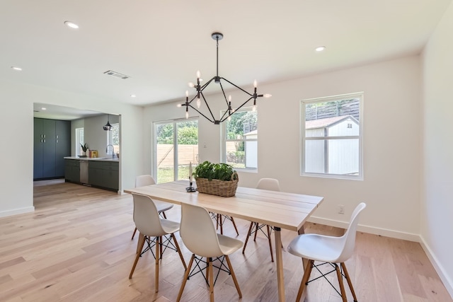 dining room with plenty of natural light, light hardwood / wood-style floors, and a chandelier