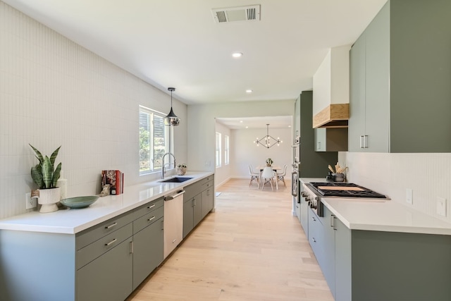 kitchen with sink, decorative backsplash, light hardwood / wood-style floors, stainless steel dishwasher, and pendant lighting