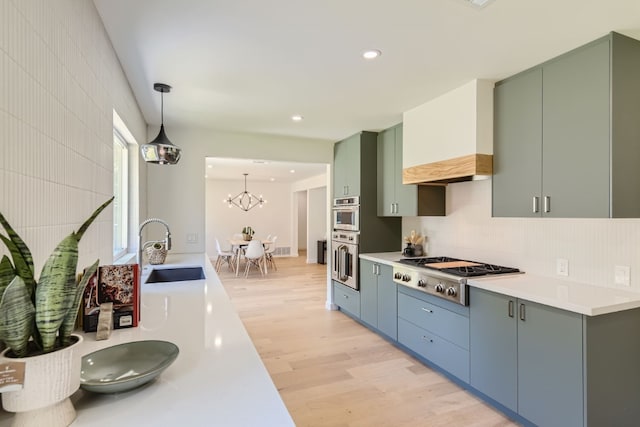 kitchen featuring sink, light hardwood / wood-style floors, tasteful backsplash, stainless steel appliances, and pendant lighting