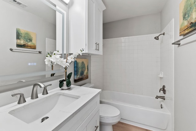 full bathroom with hardwood / wood-style flooring, vanity, tiled shower / bath combo, and toilet