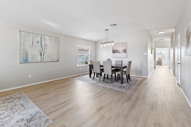 dining room with light hardwood / wood-style floors and a chandelier