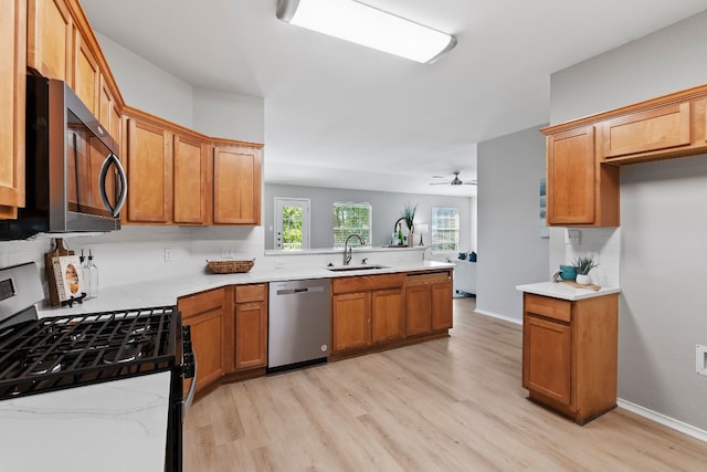 kitchen with stainless steel appliances, light hardwood / wood-style flooring, sink, kitchen peninsula, and ceiling fan