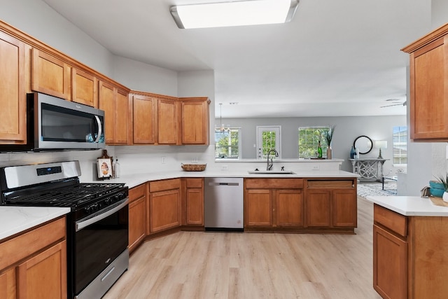 kitchen with stainless steel appliances, sink, light wood-type flooring, kitchen peninsula, and ceiling fan