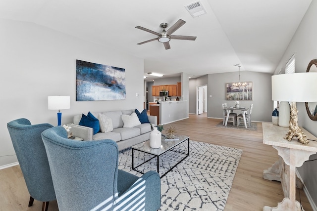 living room with light hardwood / wood-style floors, ceiling fan with notable chandelier, and lofted ceiling