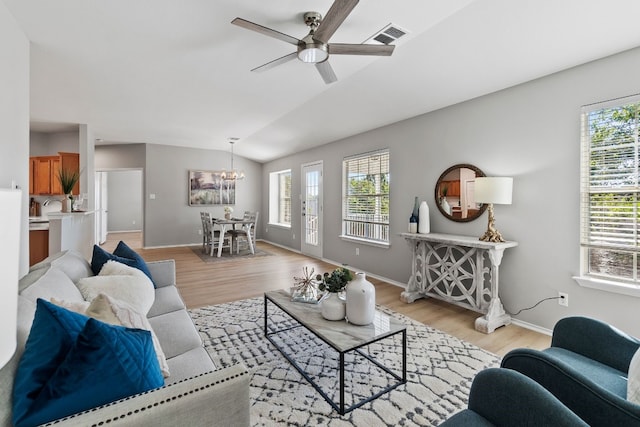 living room with light hardwood / wood-style flooring, vaulted ceiling, and ceiling fan with notable chandelier