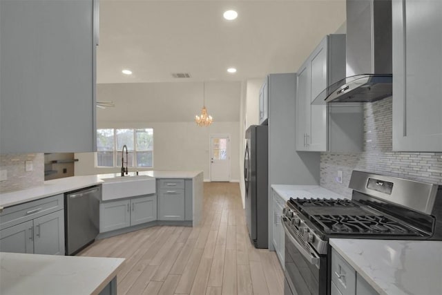 kitchen with stainless steel appliances, visible vents, gray cabinetry, a sink, and wall chimney exhaust hood