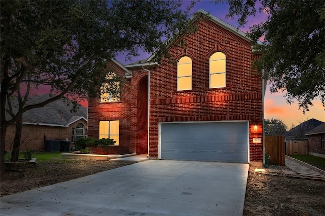 traditional-style home featuring brick siding, concrete driveway, an attached garage, central AC, and fence