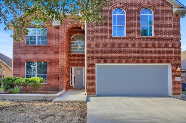 traditional-style house with driveway, brick siding, central AC, and an attached garage