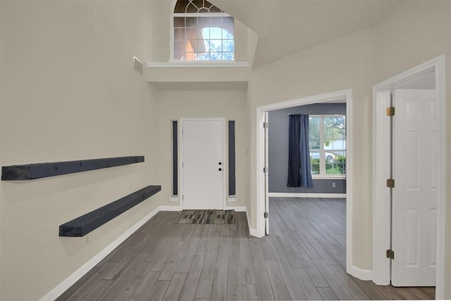 entrance foyer with baseboards, a high ceiling, visible vents, and wood finished floors