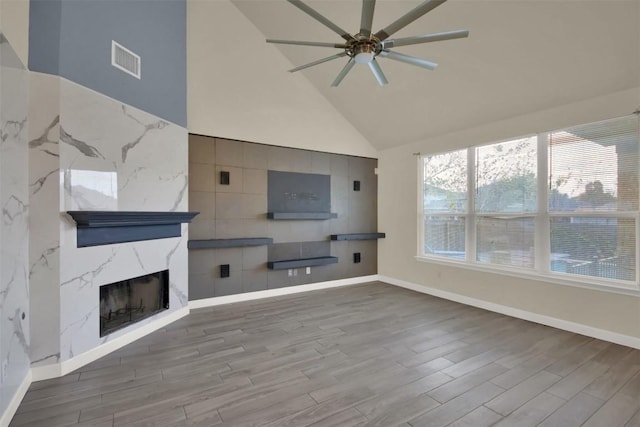 unfurnished living room with visible vents, a high end fireplace, ceiling fan, wood finished floors, and baseboards