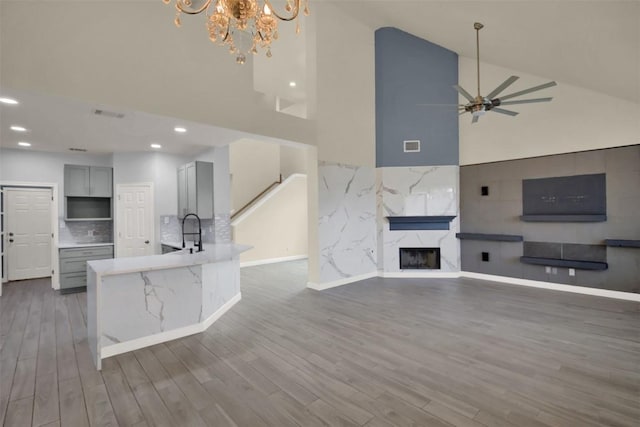 kitchen with open floor plan, a peninsula, gray cabinets, and a high end fireplace