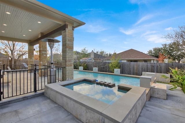 view of swimming pool with a fenced backyard, a fenced in pool, and an in ground hot tub