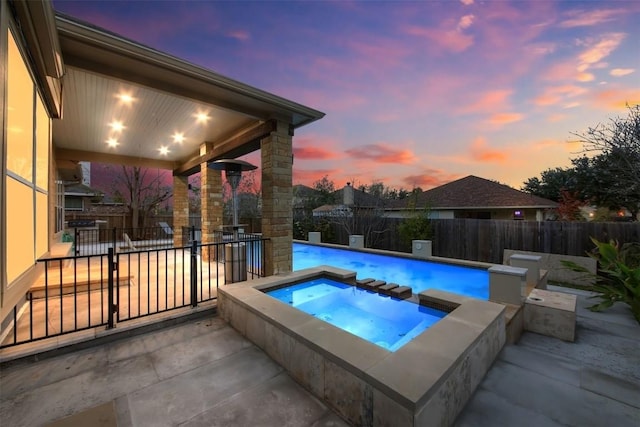 pool at dusk with a fenced in pool, a fenced backyard, a patio, and an in ground hot tub