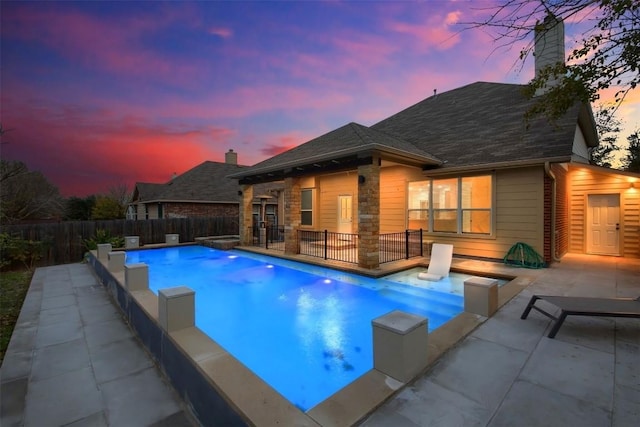 pool at dusk with a patio area, fence, and a fenced in pool