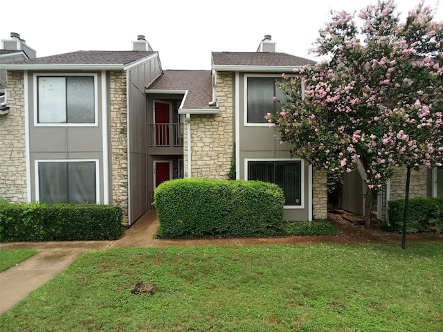 multi unit property featuring a shingled roof, a front lawn, and stucco siding