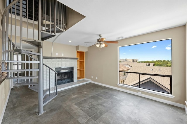 unfurnished living room featuring ceiling fan, a brick fireplace, and concrete flooring