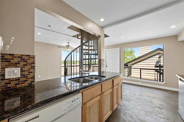 kitchen featuring dark stone counters, concrete floors, sink, dishwashing machine, and ceiling fan