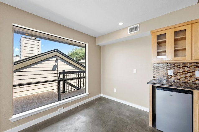 interior space with decorative backsplash, light brown cabinetry, and dishwasher