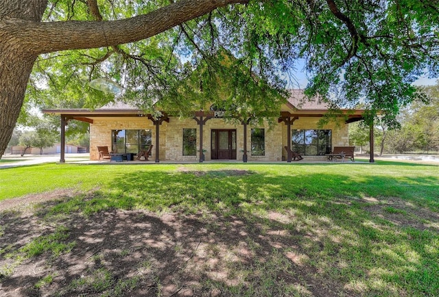 rear view of house featuring ceiling fan, a patio area, and a lawn