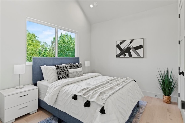 bedroom featuring light wood-type flooring and high vaulted ceiling