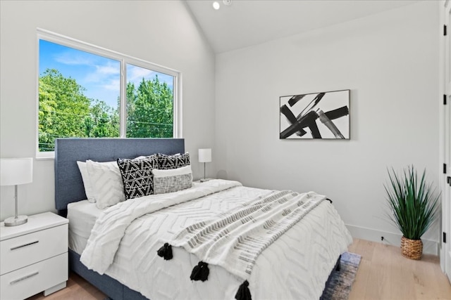 bedroom with vaulted ceiling, multiple windows, and light wood-type flooring