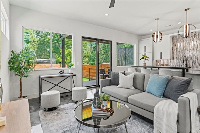 living room featuring a wealth of natural light, an inviting chandelier, and sink