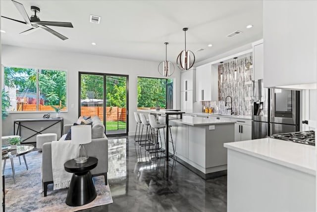 kitchen featuring white cabinets, backsplash, a healthy amount of sunlight, and pendant lighting