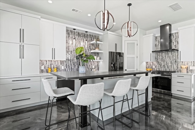 kitchen featuring appliances with stainless steel finishes, decorative backsplash, wall chimney exhaust hood, and hanging light fixtures