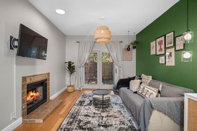 living room featuring a tiled fireplace and light hardwood / wood-style flooring