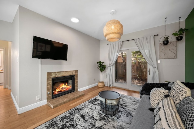 living room with a tiled fireplace, wood finished floors, and baseboards