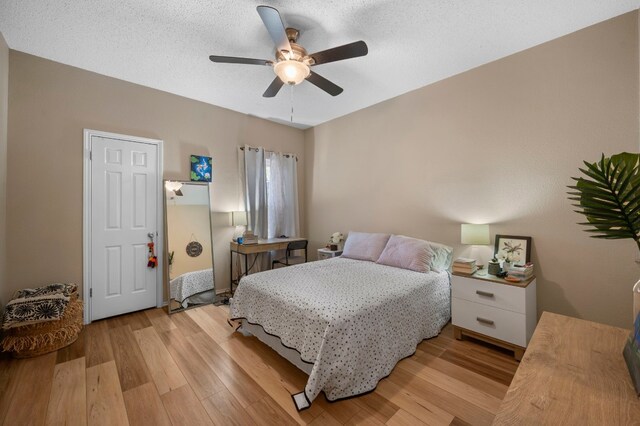 bedroom with ceiling fan, light wood-type flooring, and a textured ceiling