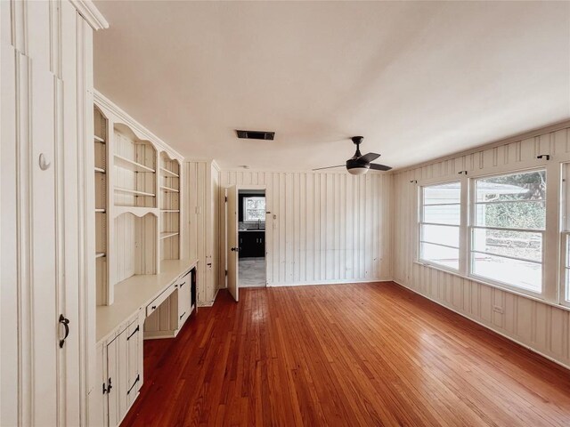 interior space featuring ceiling fan, crown molding, built in shelves, and dark hardwood / wood-style floors