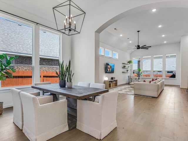 dining area featuring ceiling fan with notable chandelier, light wood-type flooring, and a wealth of natural light