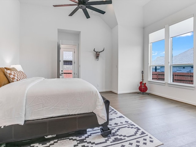 bedroom with ceiling fan, vaulted ceiling, wood-type flooring, and multiple windows