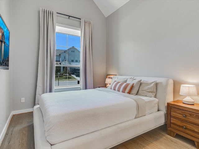 bedroom featuring hardwood / wood-style flooring, vaulted ceiling, and multiple windows