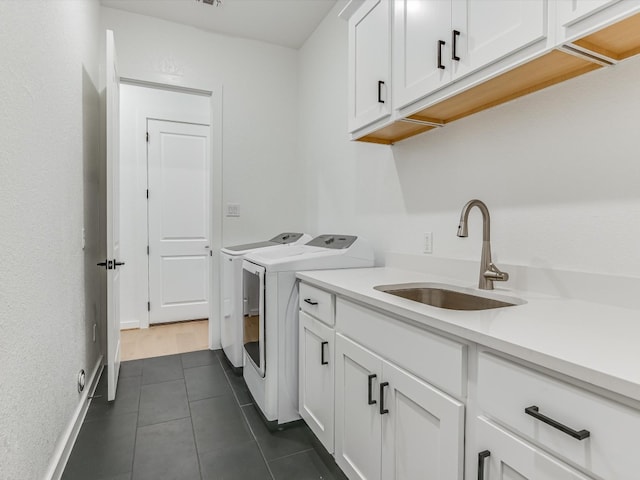 washroom with cabinets, washing machine and dryer, dark tile patterned floors, and sink