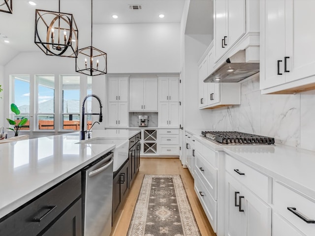 kitchen featuring white cabinetry, light hardwood / wood-style flooring, hanging light fixtures, and appliances with stainless steel finishes