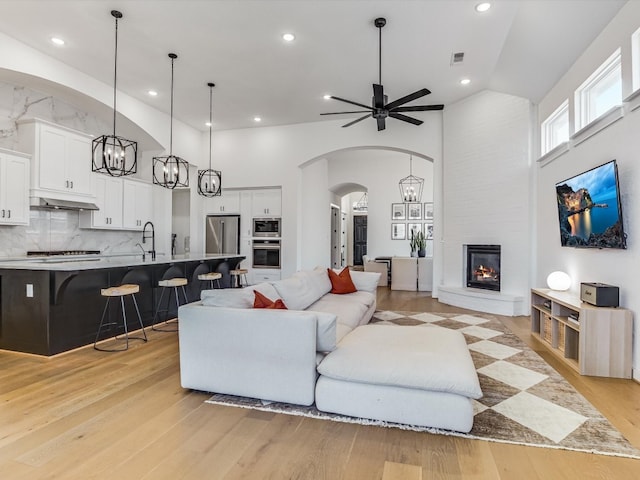 living room with ceiling fan, high vaulted ceiling, and light wood-type flooring