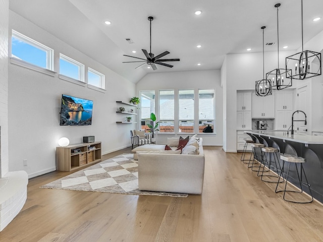 living room with light hardwood / wood-style floors, high vaulted ceiling, ceiling fan, and sink