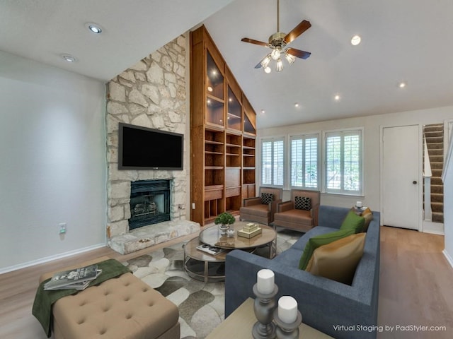 living room with high vaulted ceiling, a fireplace, light wood-type flooring, and ceiling fan