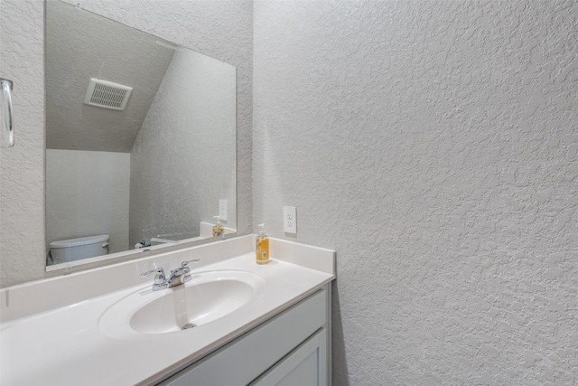 bathroom with vaulted ceiling, toilet, and vanity