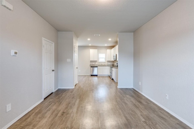 unfurnished living room with baseboards, recessed lighting, and light wood finished floors