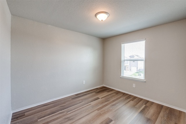 unfurnished room featuring hardwood / wood-style flooring and a textured ceiling